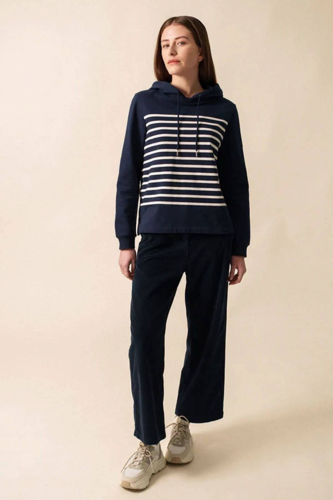 Chandail à capuche marin à rayures horizontales, porté avec un pantalon décontracté, style casual chic.