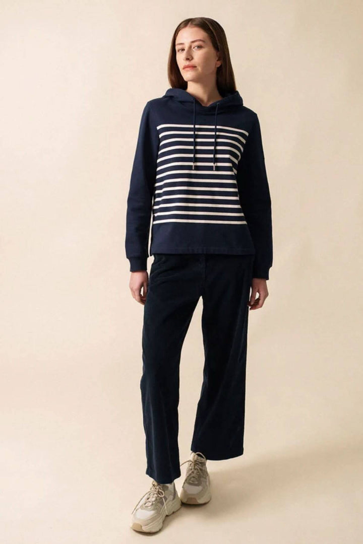 Chandail à capuche marin à rayures horizontales, porté avec un pantalon décontracté, style casual chic.