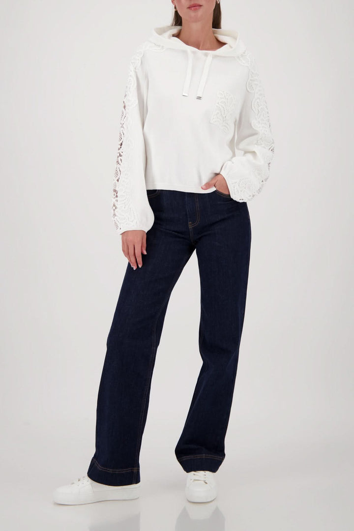 Femme portant un chandail à capuchon avec broderies décoratives, ajusté et élégant, combiné à un jean pour un look décontracté.