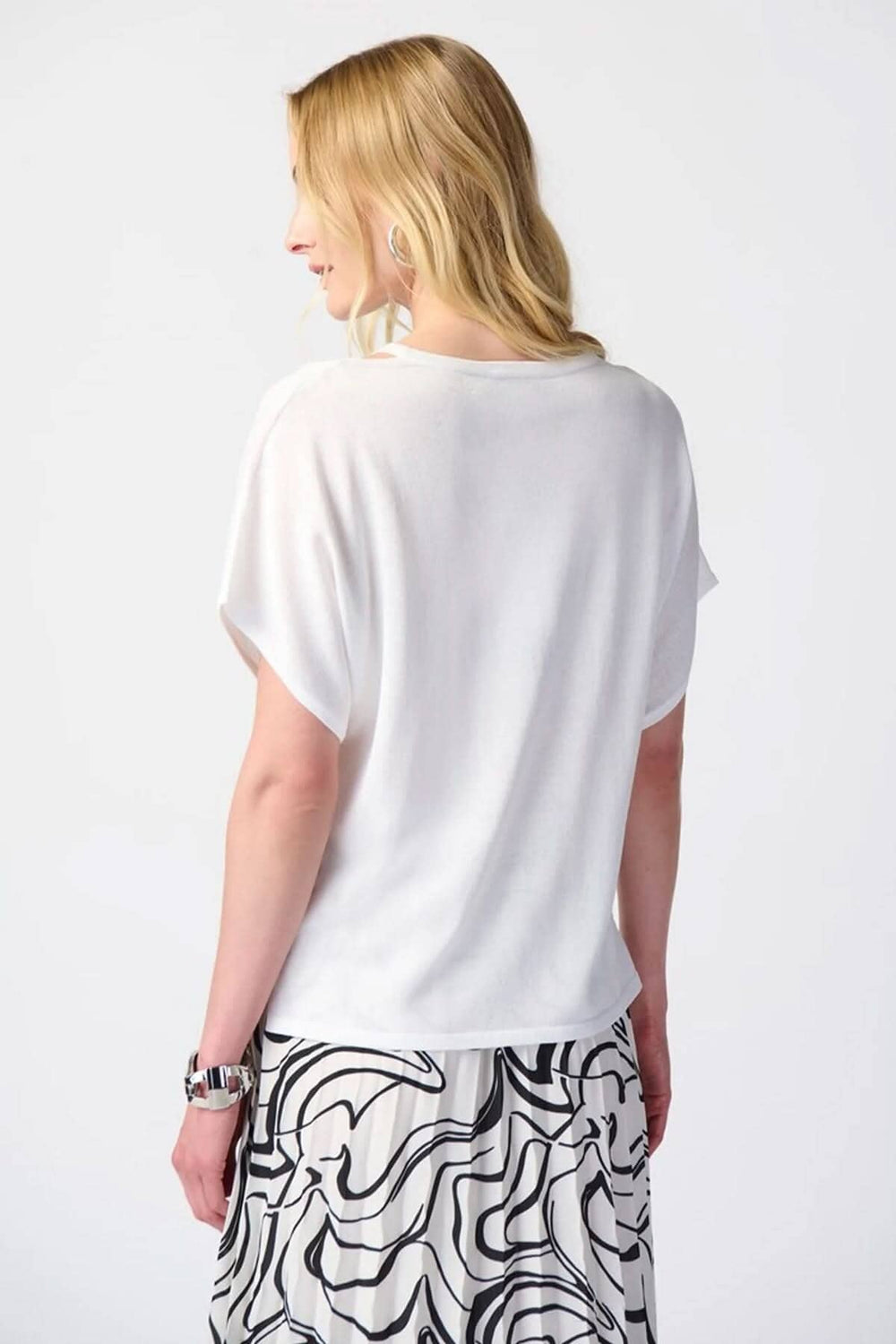 Femme portant un chandail col en V blanc avec manches courtes, aperçu de l'arrière, style élégant et décontracté.