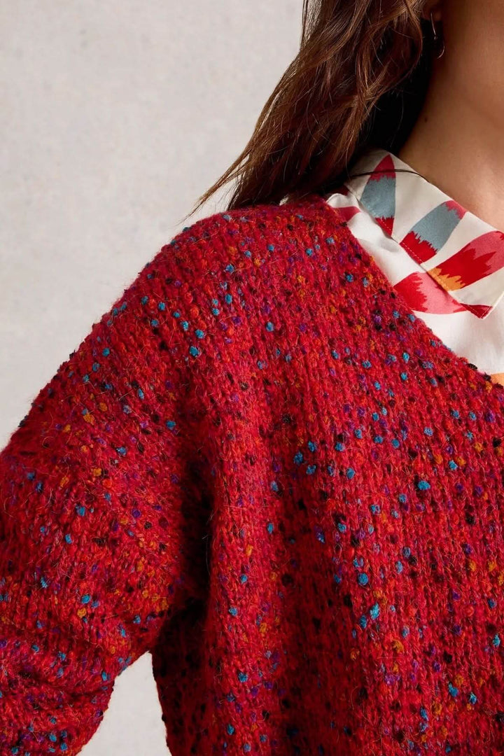 Chandail col en V en maille rouge chinée, porté sur une chemise à motifs pour une touche de style décontracté.