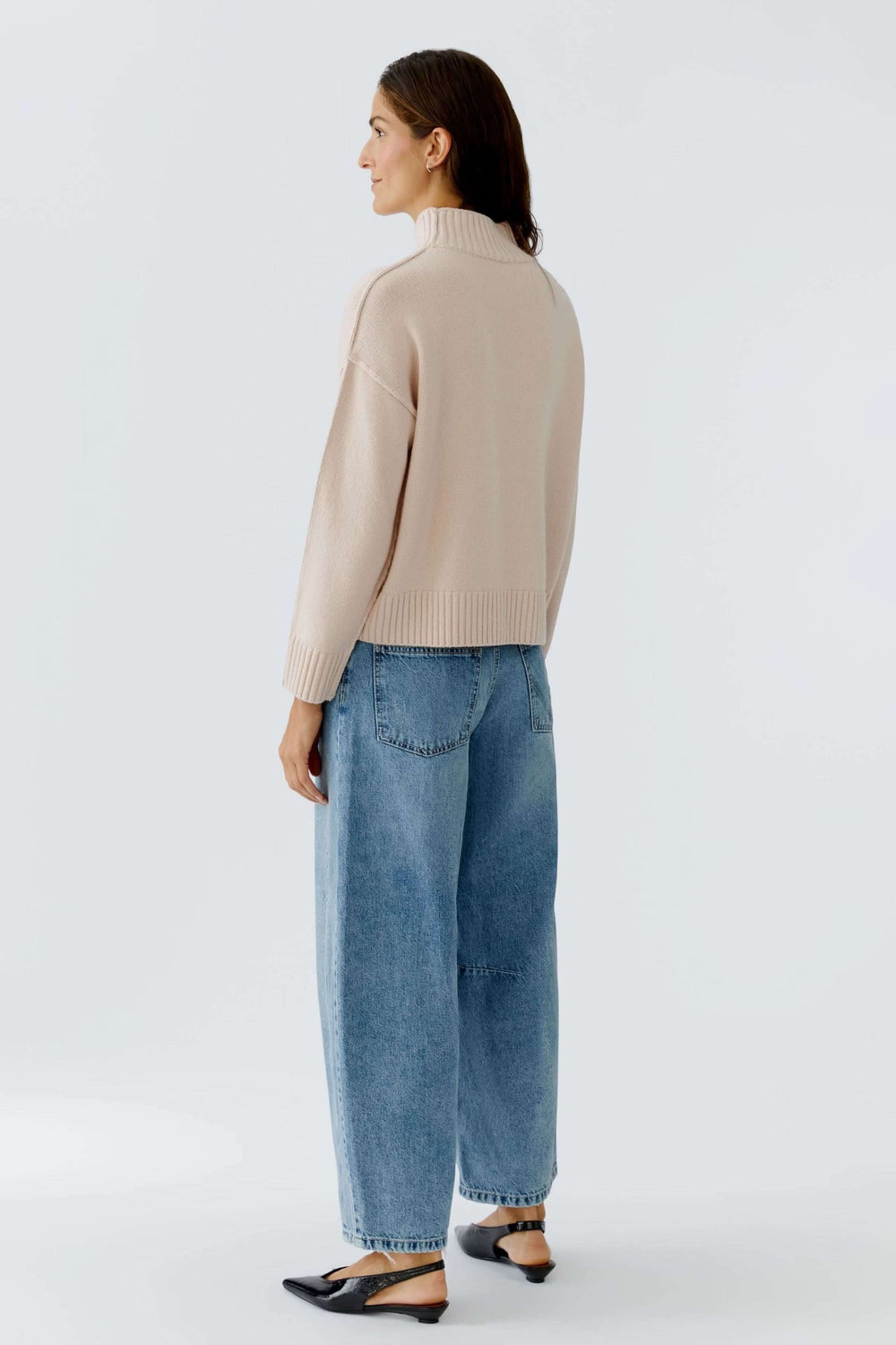 Femme portant un chandail à col montant en maille douce beige avec un jean ample, vue arrière.