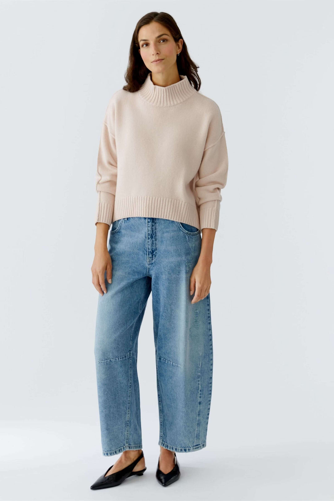Chandail à col montant en maille douce porté avec un jean pour un look moderne et minimaliste.