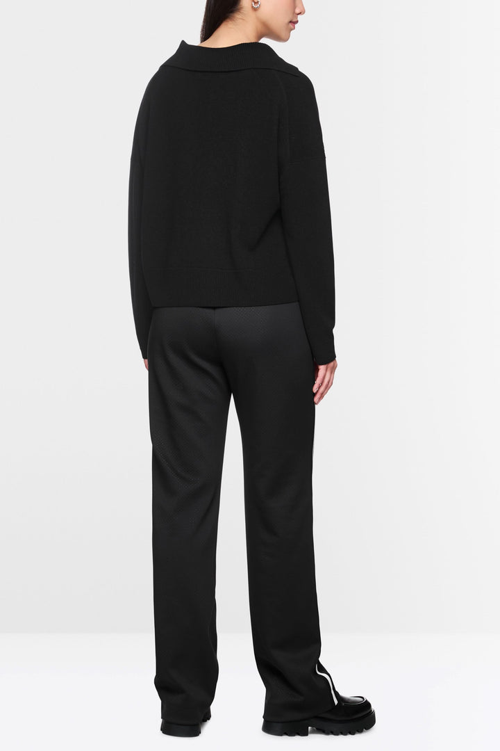 Chandail col ouvert noir élégant avec coupe décontractée, vu de dos avec un pantalon fluide.