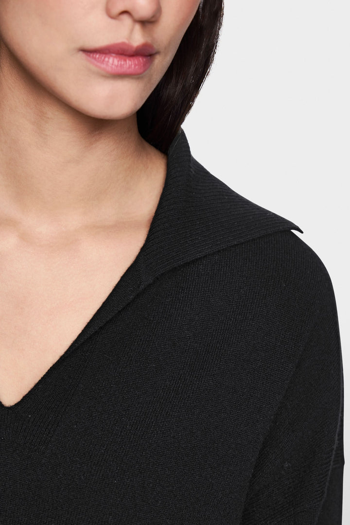 Détail d'un chandail col ouvert noir avec maille douce et coupe décontractée.