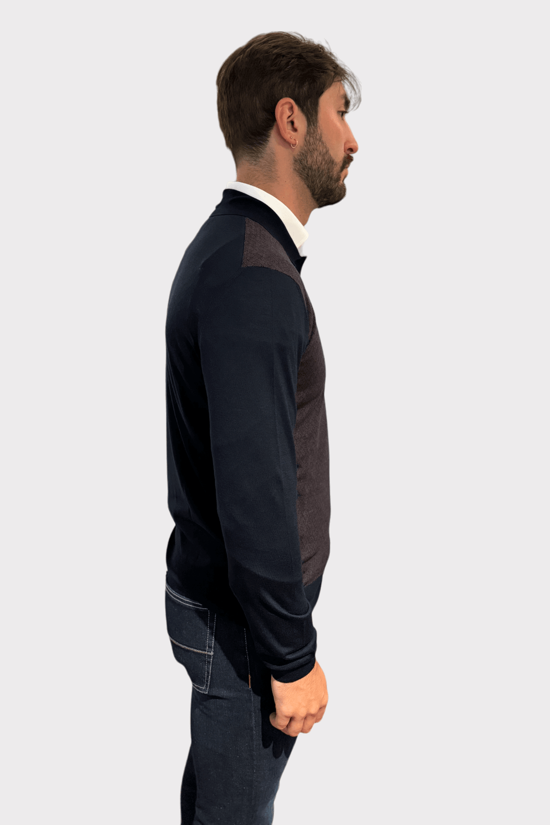 Homme portant un chandail à col polo moderne avec motif géométrique, vu de profil.