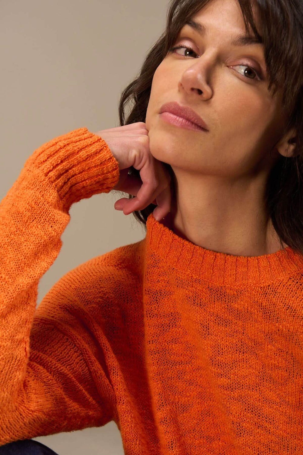 Femme portant un chandail à col rond orange en coton bio, avec une coupe décontractée et des manches longues.