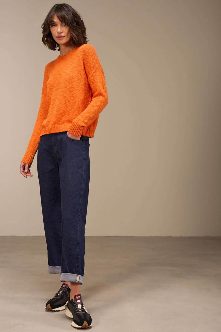 Pull à col rond orange en coton bio, stylé avec un jean noir, décontracté et moderne, tenant un look minimaliste.