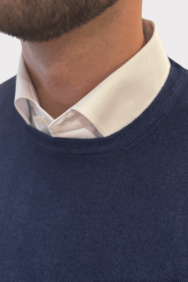 Chandail col rond en laine bleu marine porté avec une chemise blanche, mettant en avant le luxe et le confort.