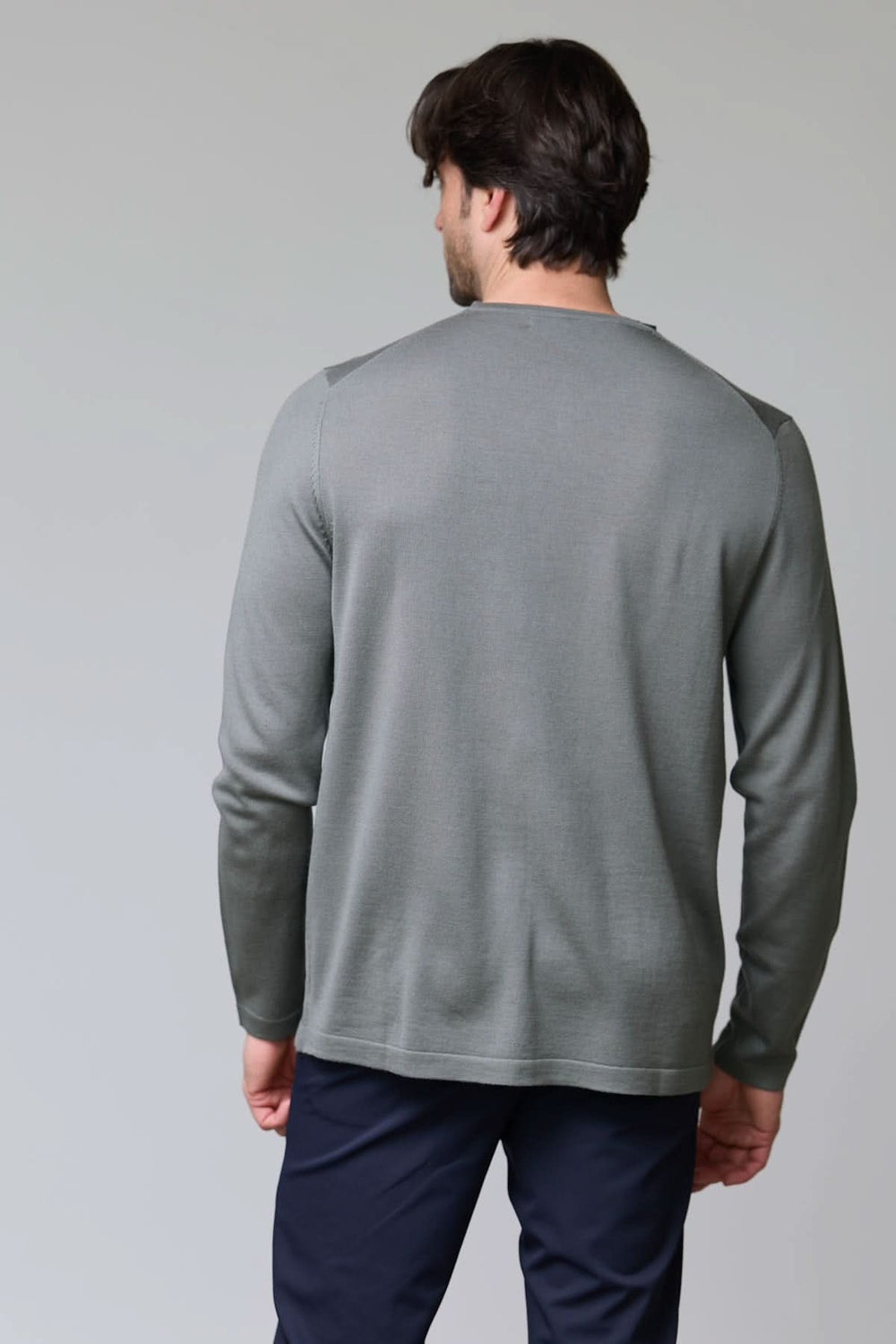 Homme portant un chandail col rond en tricot fin gris de dos, texture douce et coupe ajustée. Décris moi le produit en français.