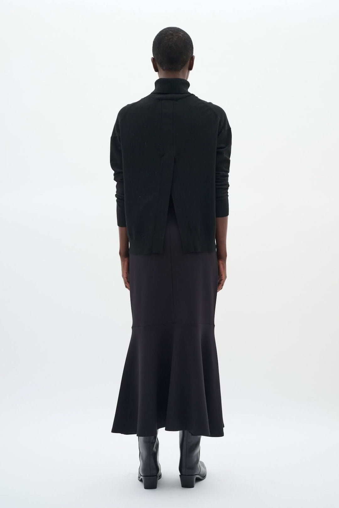 Chandail à col roulé noir avec coupe décontractée, porté avec une jupe longue pour un look chic.