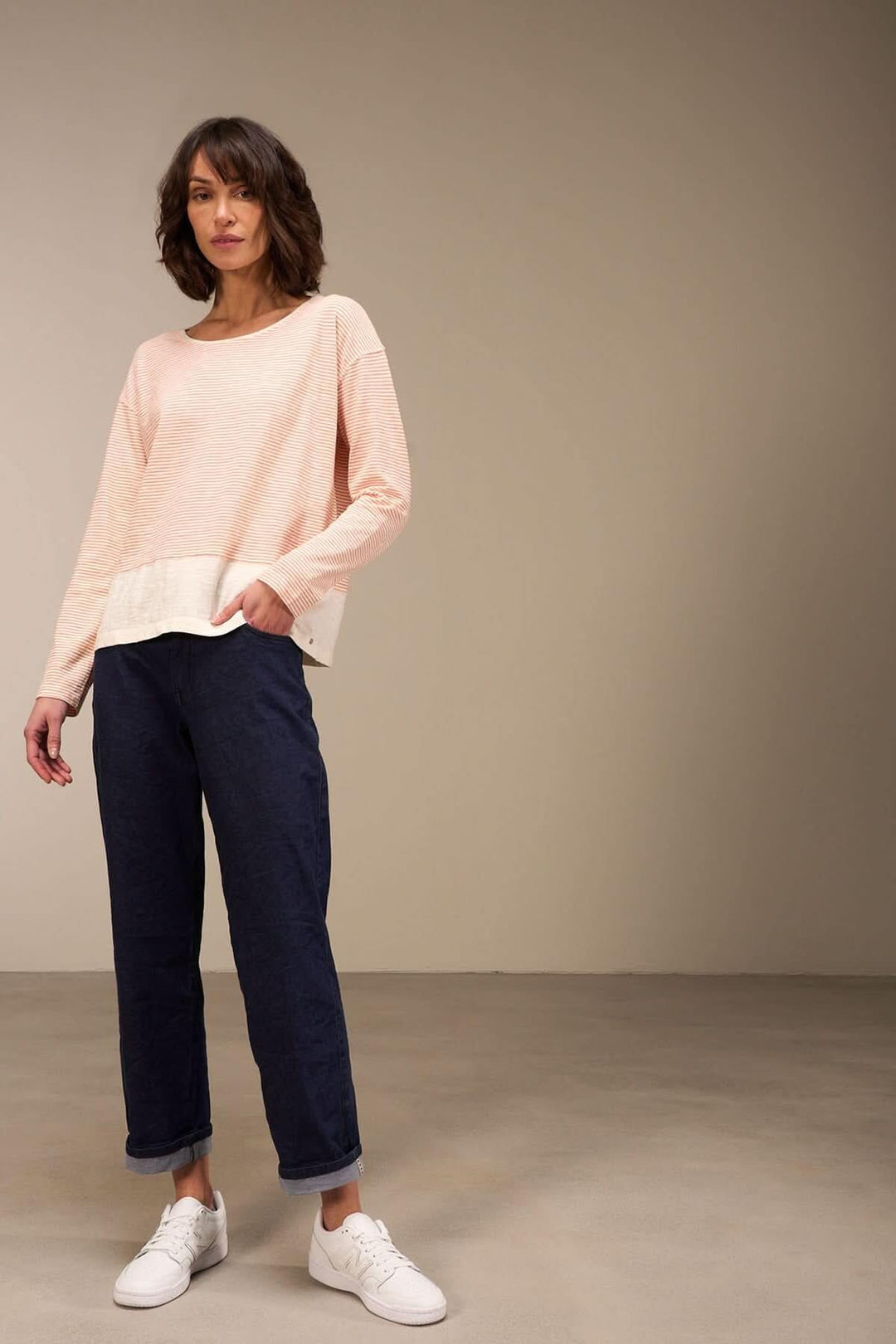 Chandail décontracté à manches longues en coton bio, accompagné de pantalon bleu foncé et sneakers blanches, style casual chic.