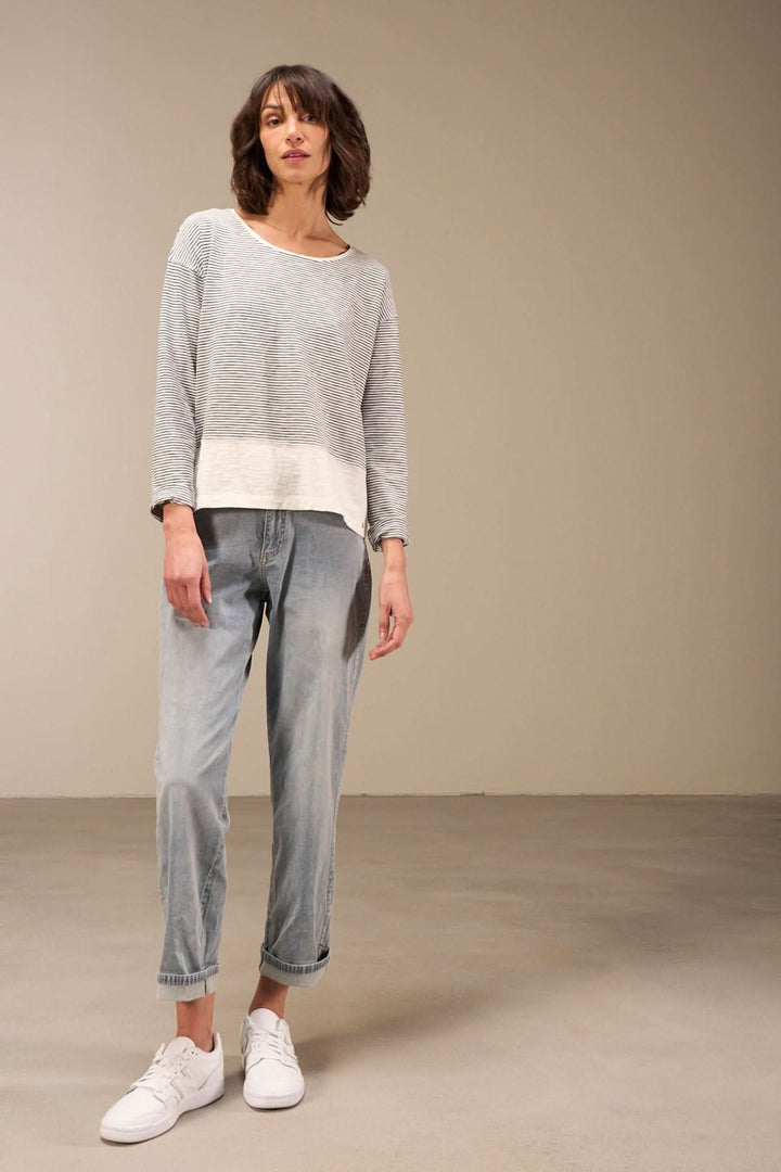 Chandail décontracté à manches longues en coton bio, col rond, porté avec un jean et des sneakers pour un style casual chic.