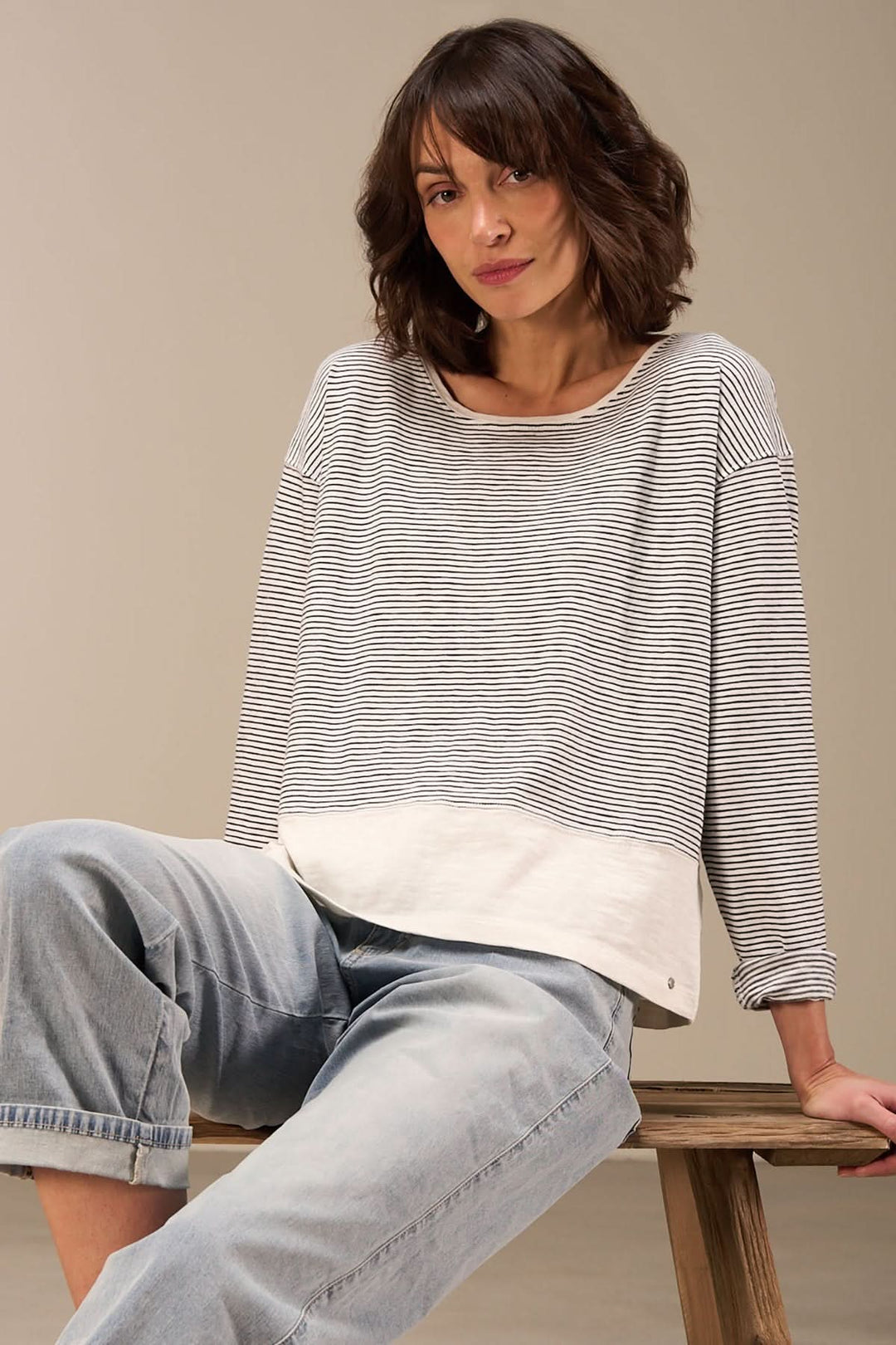 Chandail décontracté à manches longues en coton biologique, style intemporel avec rayures, porté avec un pantalon en jean.