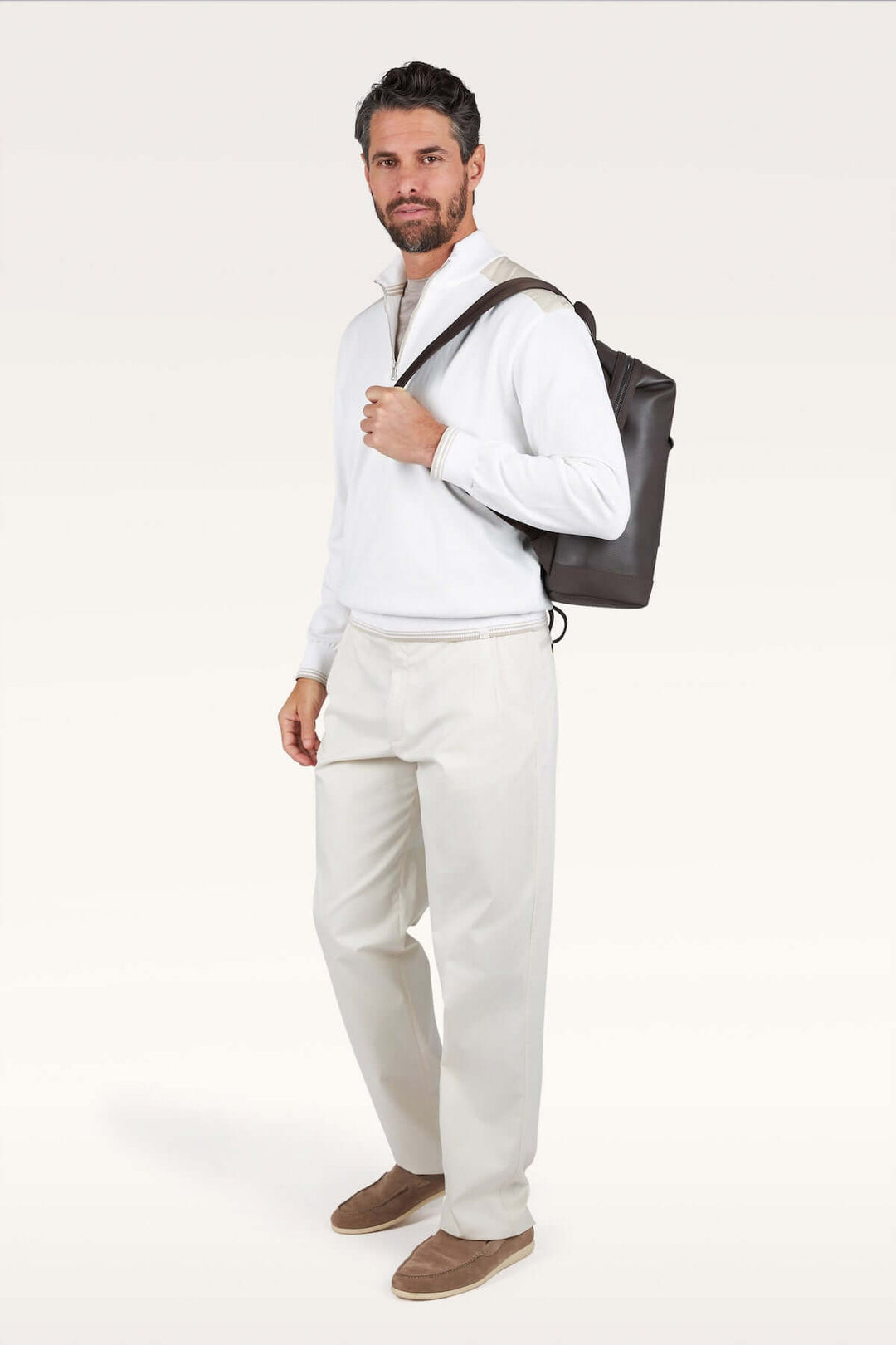 Homme portant un chandail à demi-zip blanc avec un sac à dos, symbolisant un style décontracté chic et confortable.