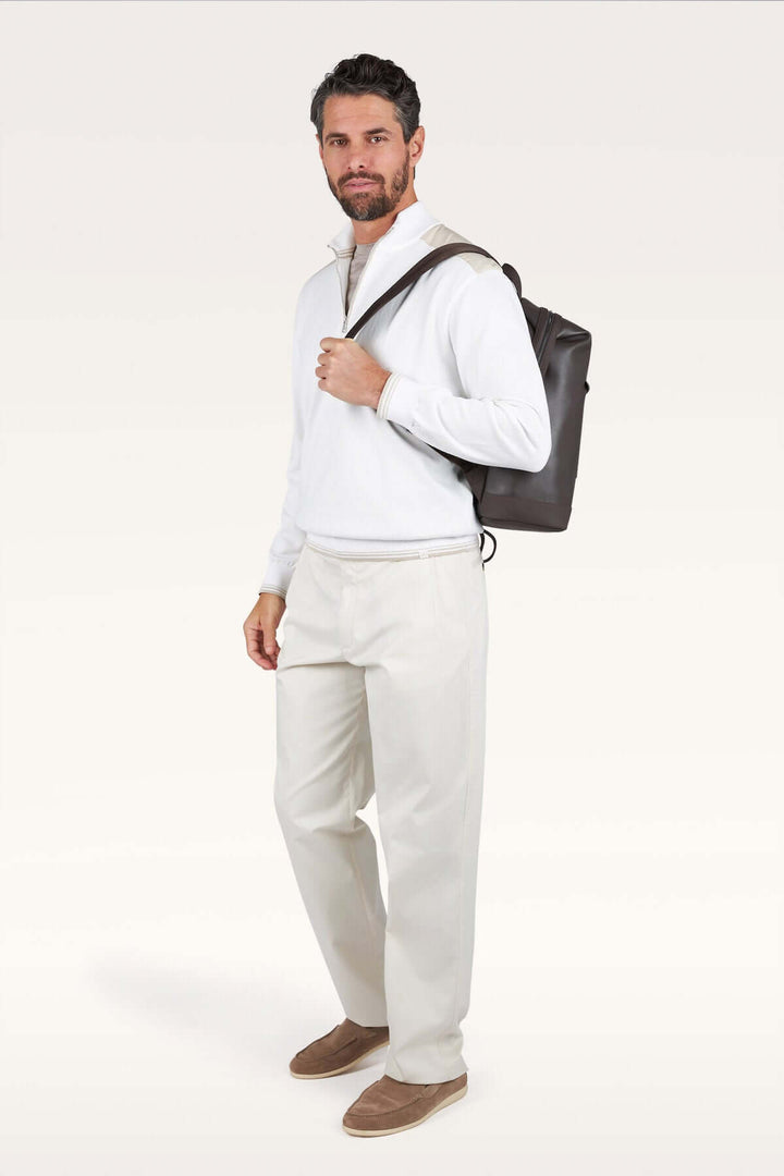 Homme portant un chandail à demi-zip blanc avec un sac à dos, symbolisant un style décontracté chic et confortable.