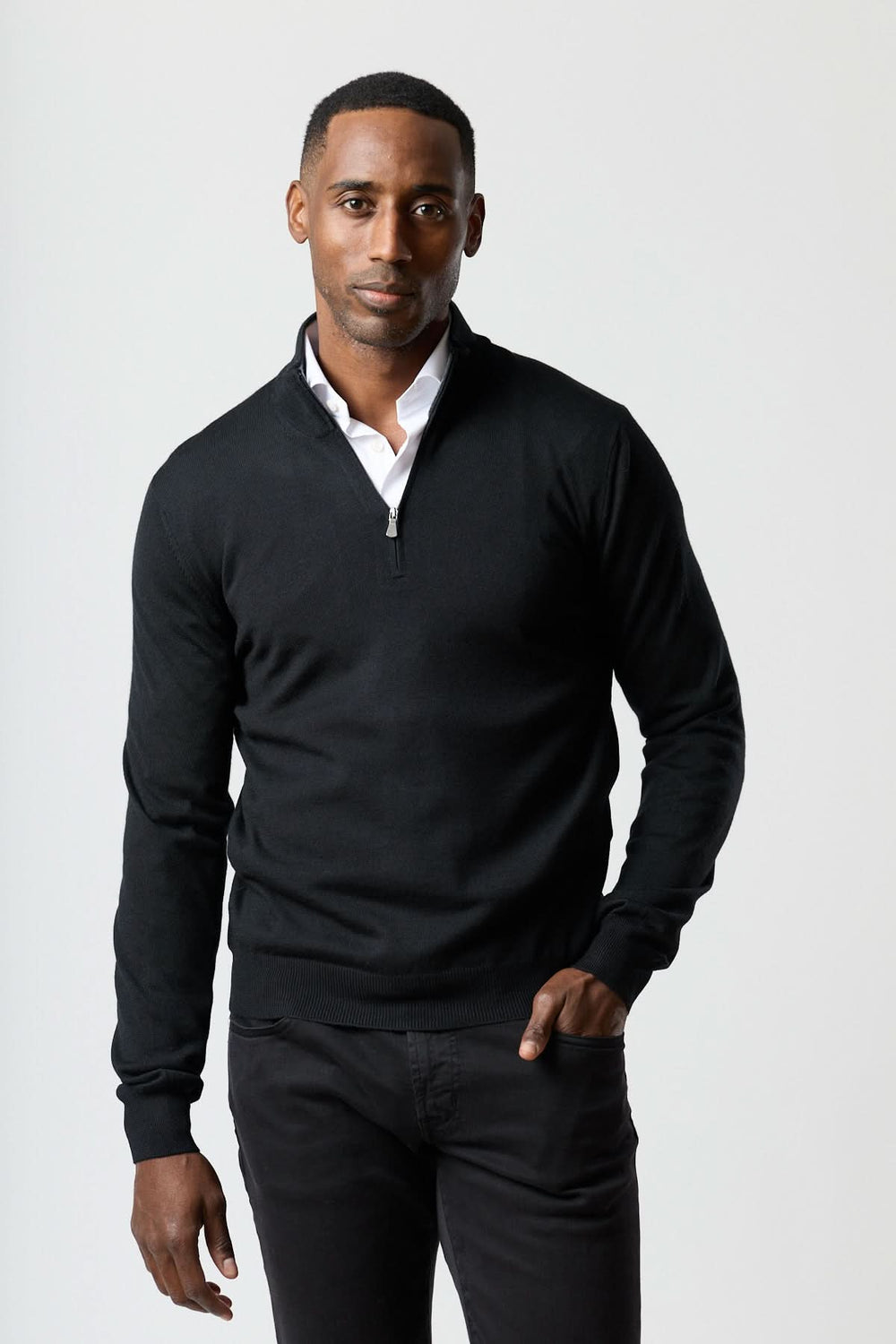 Homme portant un chandail à demi-zip en laine mérinos noir, élégant et moderne, combinant confort et style.