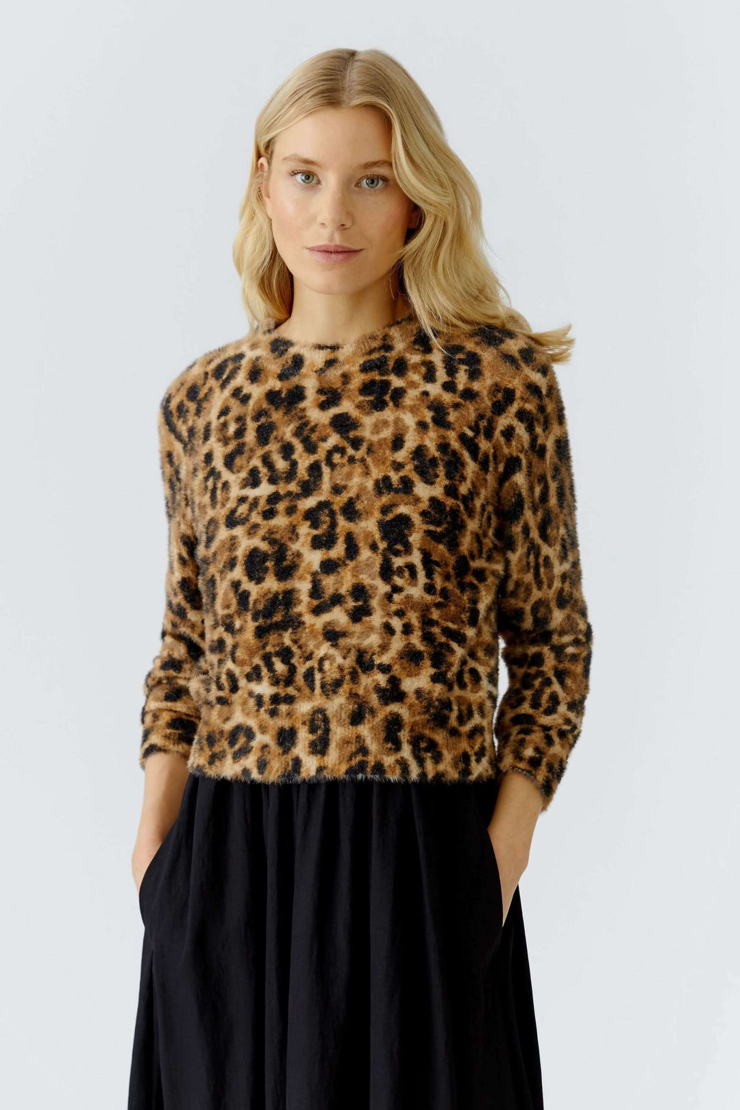 Femme portant chandail duveteux à motif animal avec encolure ronde et manches longues sur une jupe fluide noire.