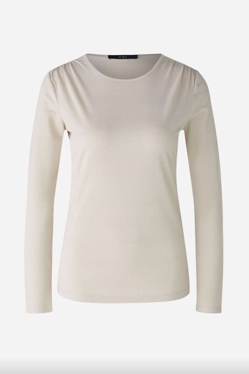 Chandail à manches longues beige avec effet brillant et volants délicats aux épaules.