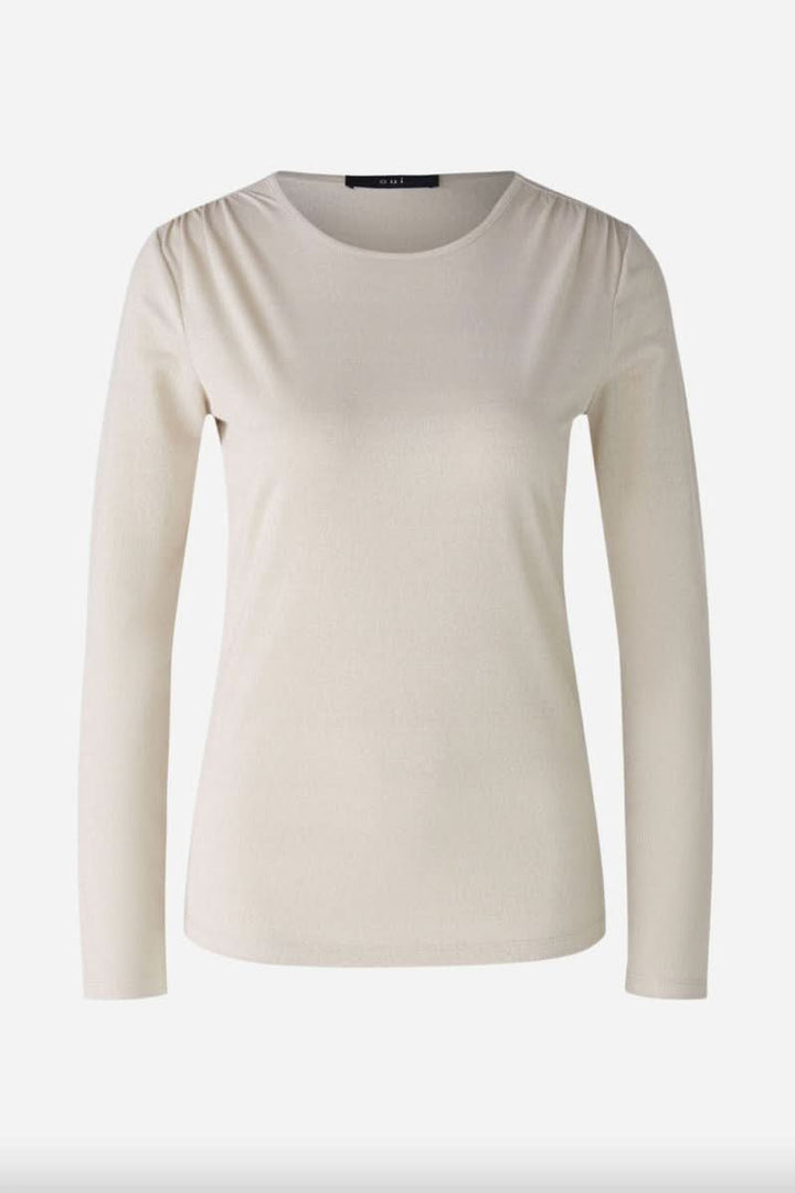 Chandail à manches longues beige avec effet brillant et volants délicats aux épaules.