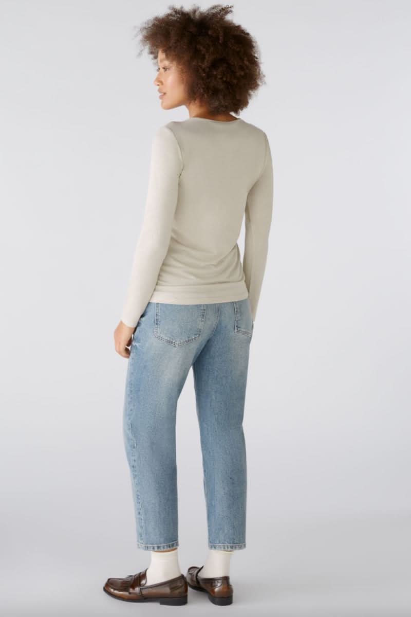 Chandail à manches longues beige avec fils métalliques, porté avec un jeans décontracté, vue de dos.