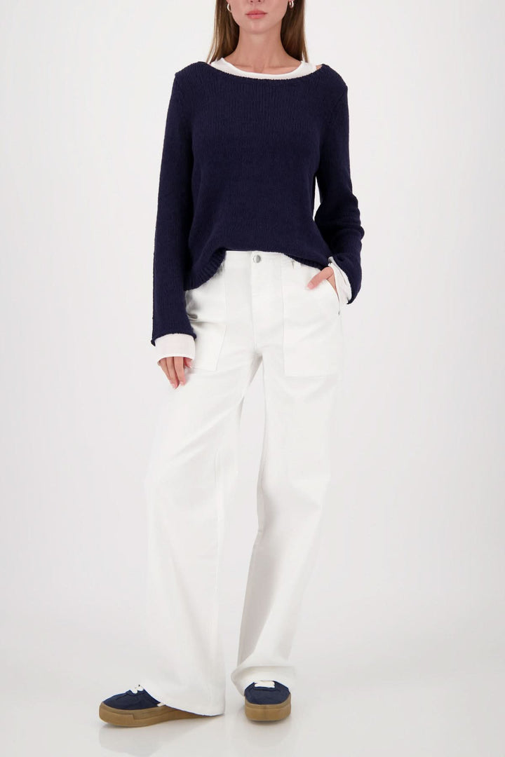 Chandail à effet superposé col rond porté avec un pantalon blanc, style moderne et polyvalent avec finitions contrastantes élégantes.