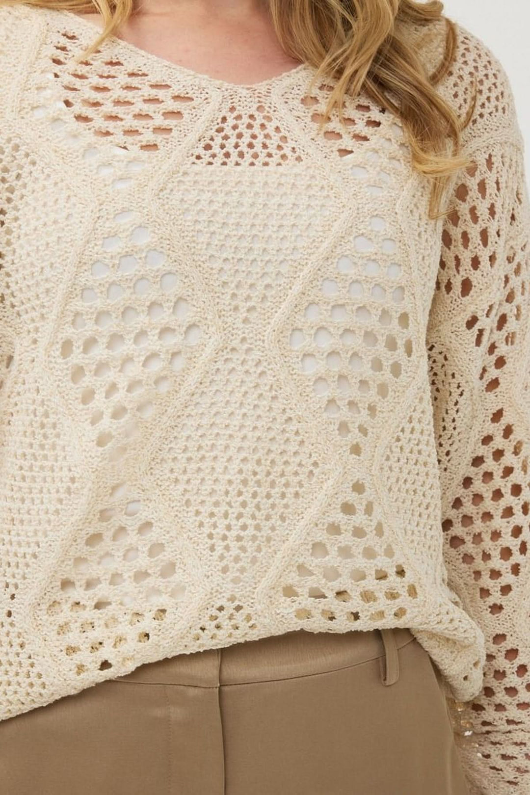 Chandail en crochet ajouré beige avec motif géométrique, col en V, manches longues et coupe fluide.