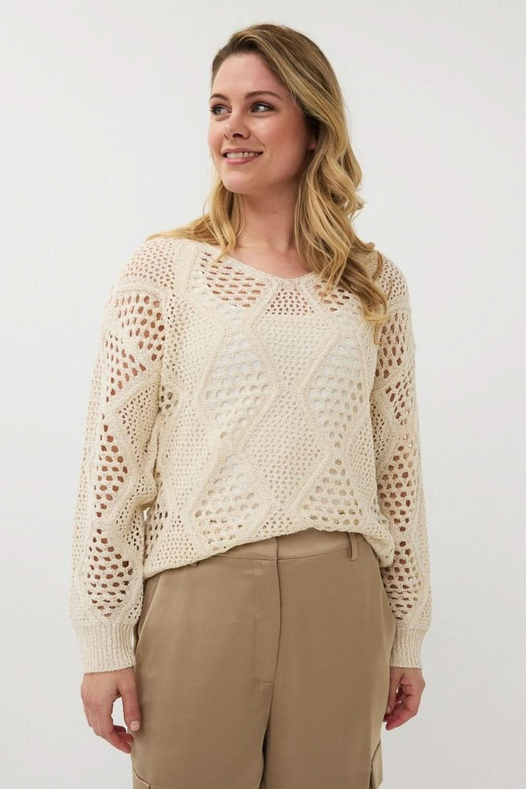 Chandail en crochet ajouré beige avec col en V, manches longues, motif géométrique, style bohème chic.
