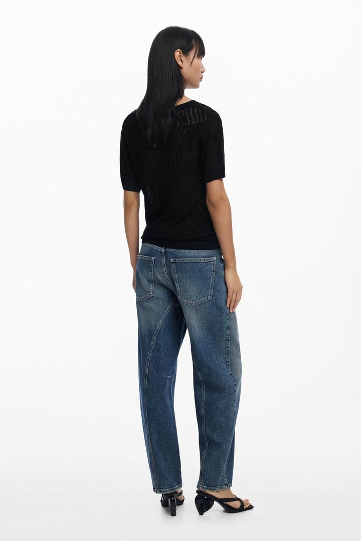 Femme vue de dos portant un chandail en maille ajourée noire et un jean décontracté, style moderne et estival.