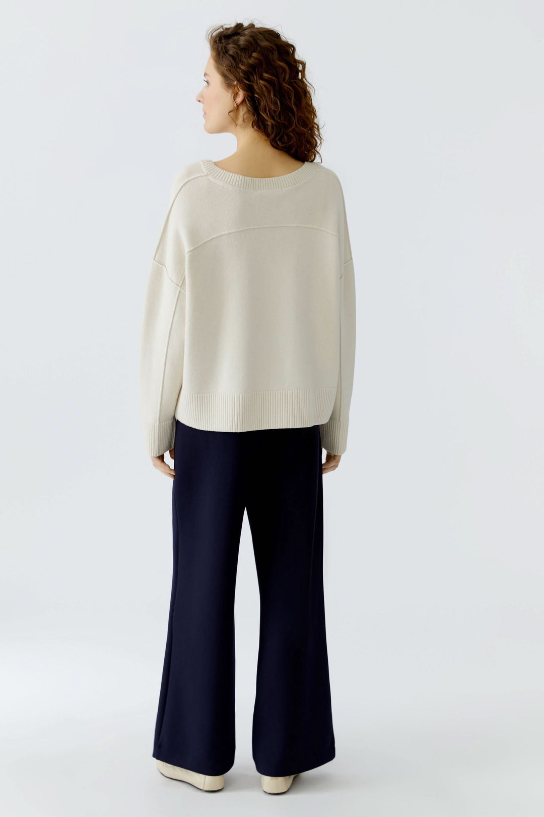 Vue arrière d'un chandail en maille à col en V, style épuré, manches longues, avec pantalon habillé, confort et modernité