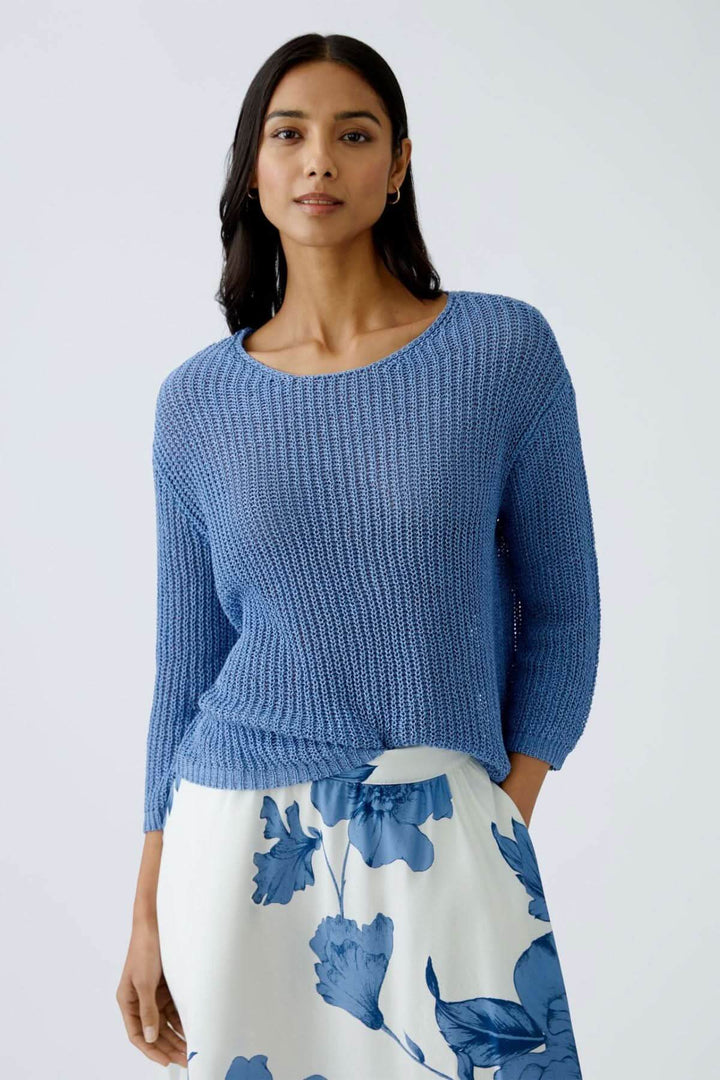Chandail en maille côtelée bleu porté avec une jupe blanche à fleurs, look décontracté et lumineux.