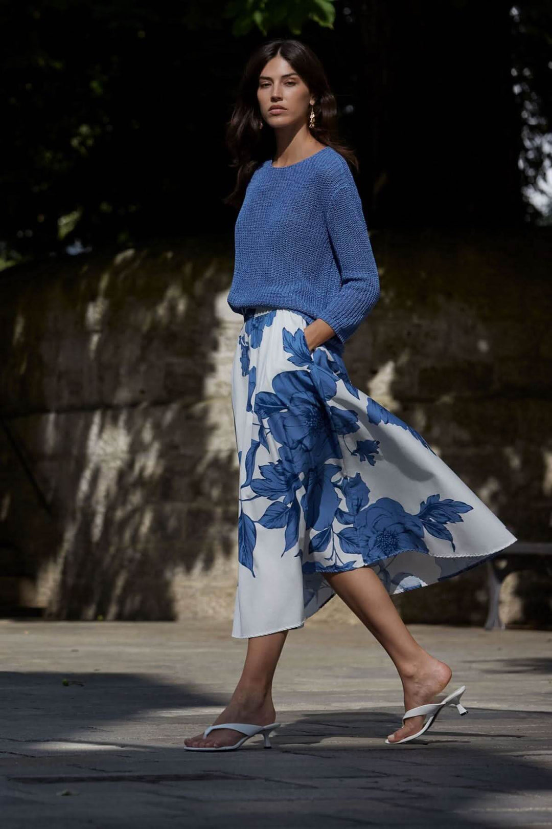 Modèle portant un chandail en maille côtelée bleu avec une jupe fluide à motifs floraux, parfait pour un look estival.