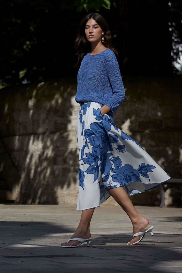 Modèle portant un chandail en maille côtelée bleu avec une jupe fluide à motifs floraux, parfait pour un look estival.