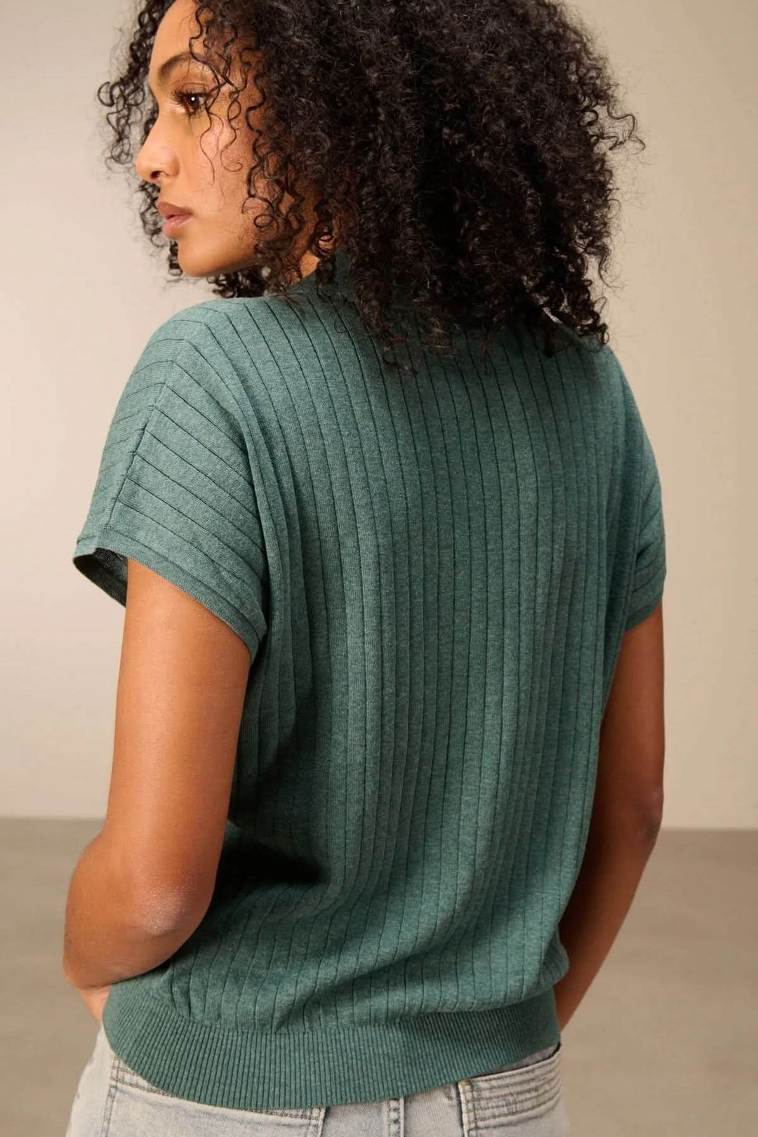 Chandail en maille fine côtelée vert avec encolure en V et col polo, porté par une femme, offrant une silhouette moderne et facile à porter.