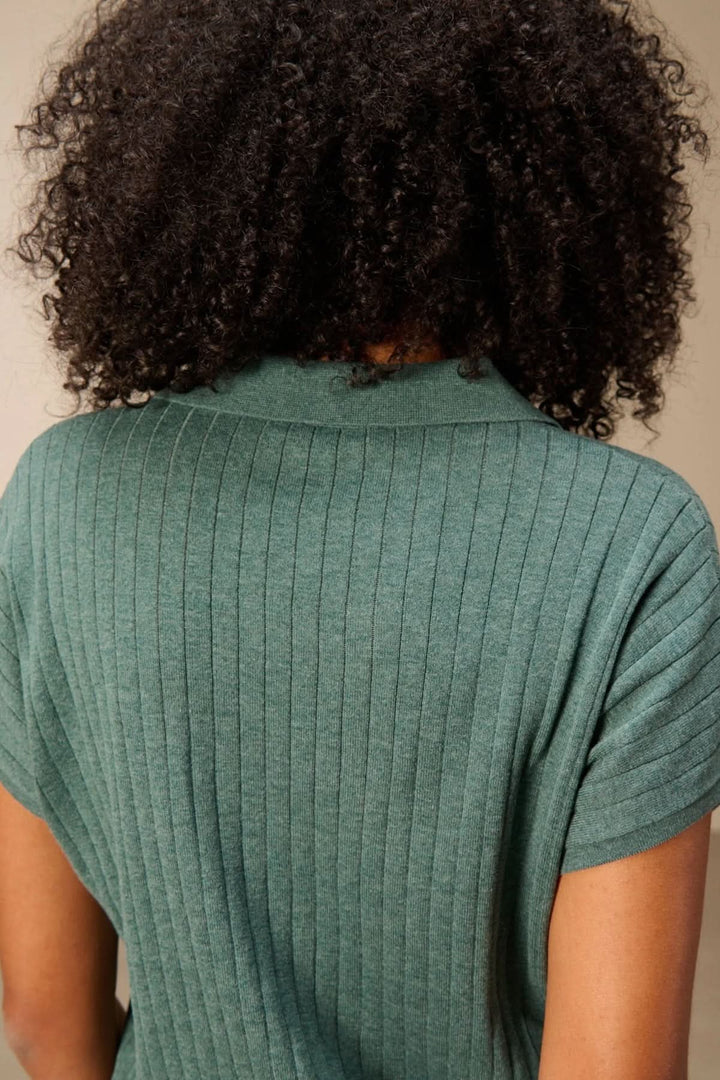 Chandail en maille fine côtelé vert avec encolure en V et col polo, montrant une silhouette moderne et confortable pour le quotidien.