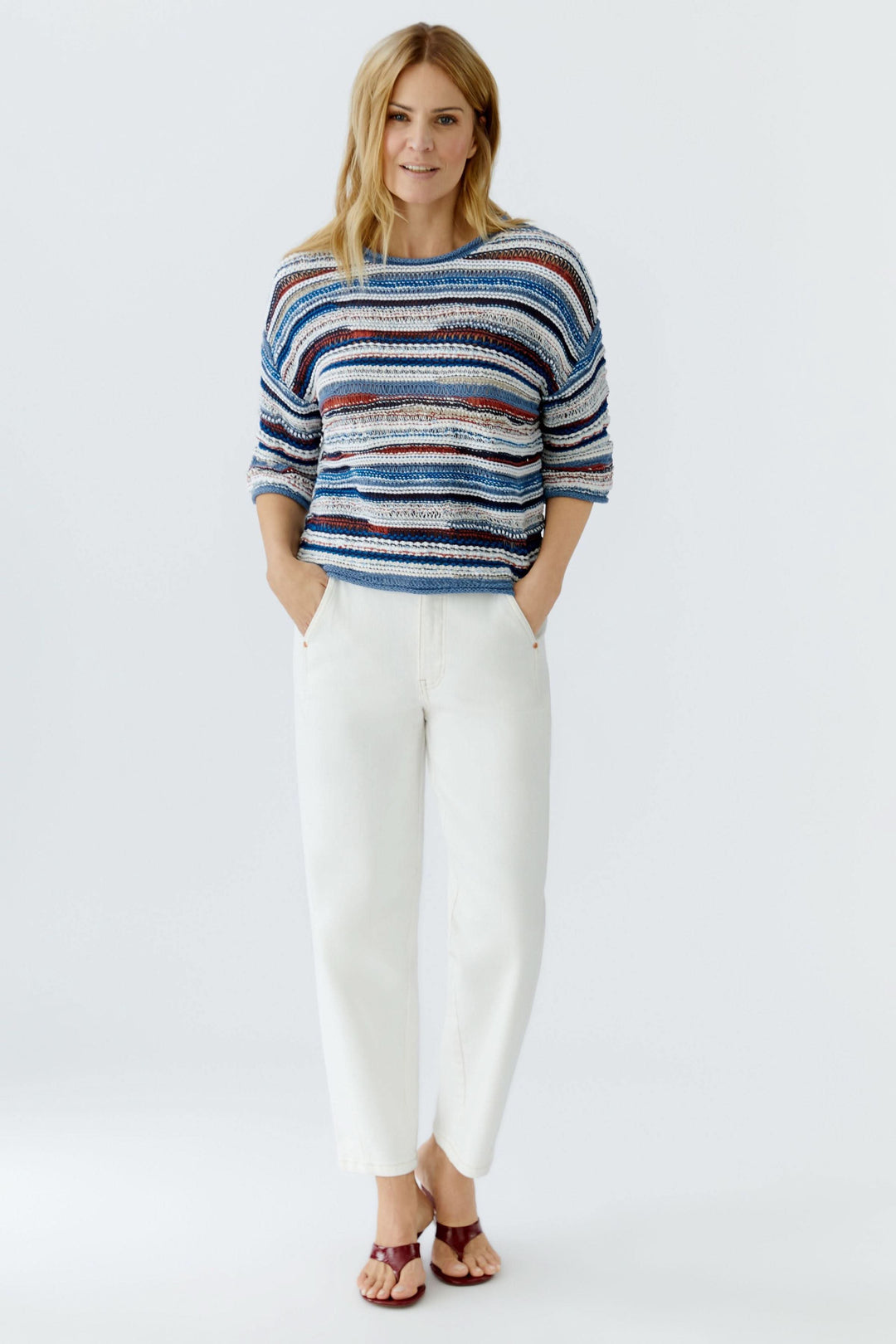 Chandail en maille multicolore à manches trois-quarts, motif rayé avec jeans blancs, style décontracté-chic idéal pour l'été.