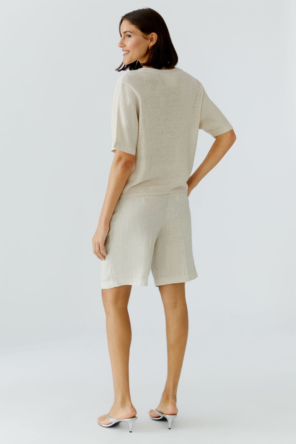 Chandail en maille texturée à manches courtes, vêtement léger beige à coupe fluide, vu de dos sur modèle féminin.
