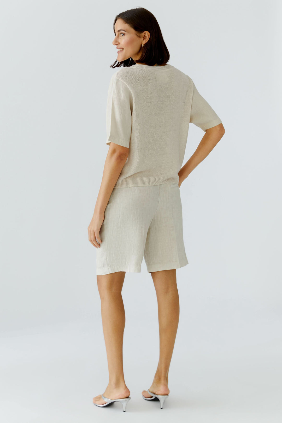Chandail en maille texturée à manches courtes, vêtement léger beige à coupe fluide, vu de dos sur modèle féminin.