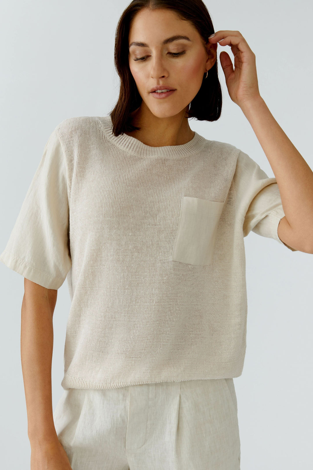 Chandail en maille texturée à manches courtes avec poche poitrine et manches en tissu contrasté, idéal pour un style naturel.