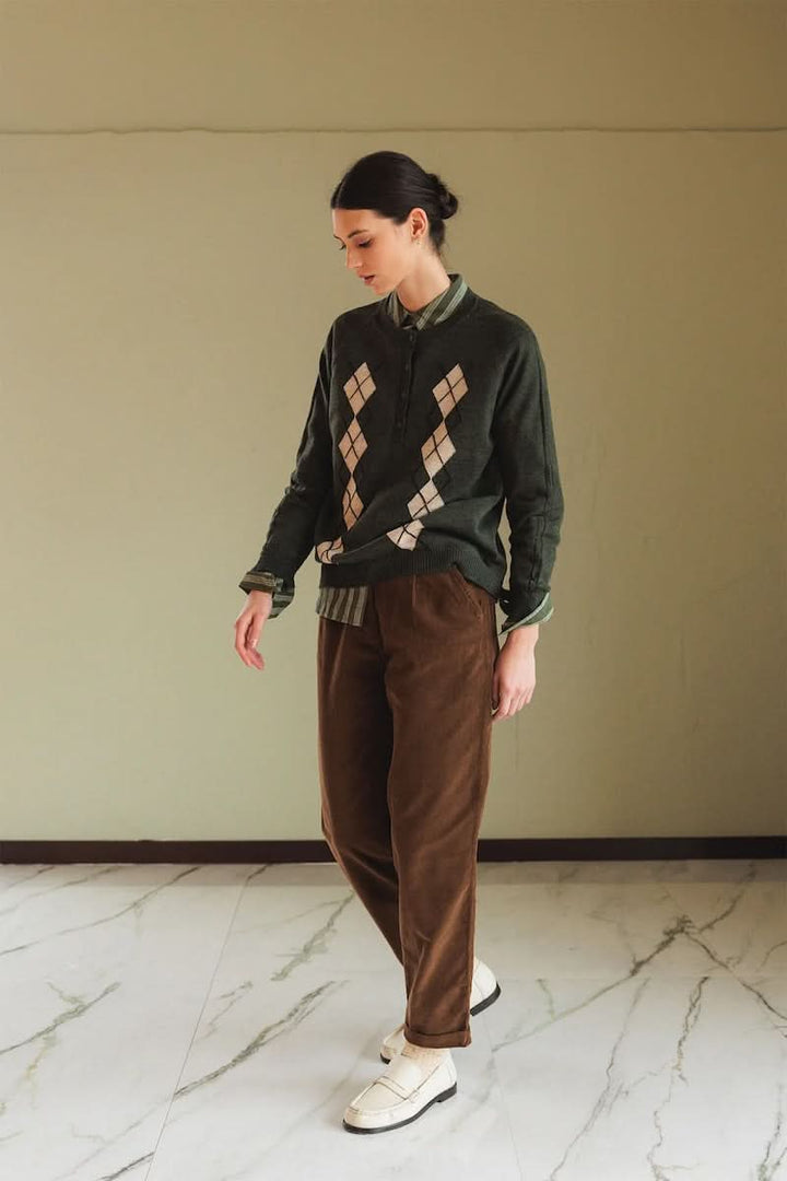 Femme portant un chandail en mérinos à motif argyle, style preppy-chic, avec chemise et pantalon décontracté.