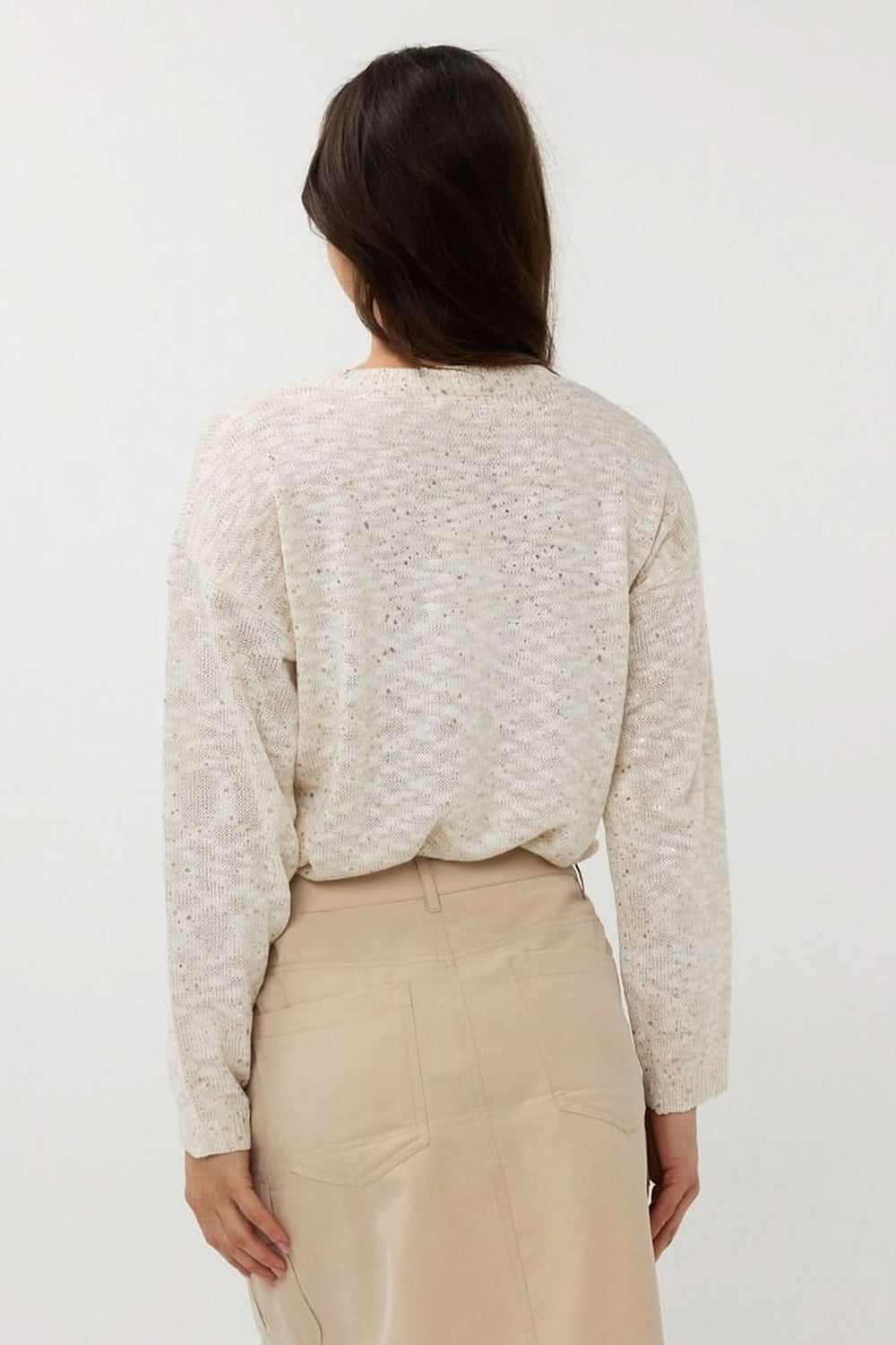 Vue arrière d'un chandail en tricot ajouré avec col rond et manches longues, associé à une jupe beige.