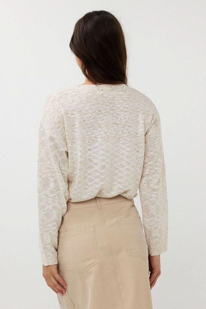 Vue arrière d'un chandail en tricot ajouré avec col rond et manches longues, associé à une jupe beige.