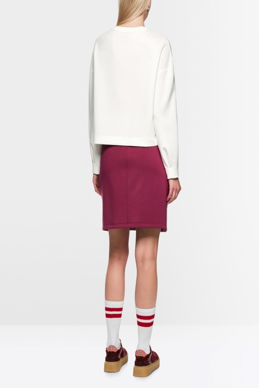 Chandail en tricot moderne avec manches longues, imprimé graphique et empiècements contrastants, porté avec jupe et chaussettes rayées blanches.