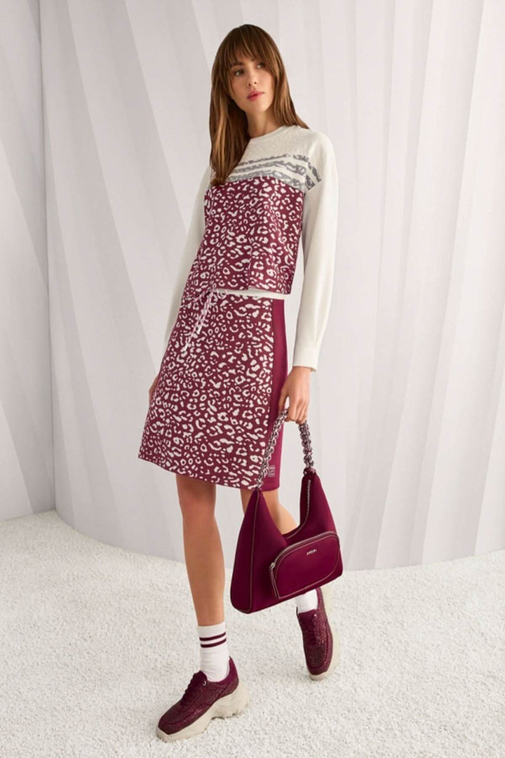 Femme portant un chandail en tricot moderne avec imprimé graphique, empiècements contrastants et sac assorti, style structuré.