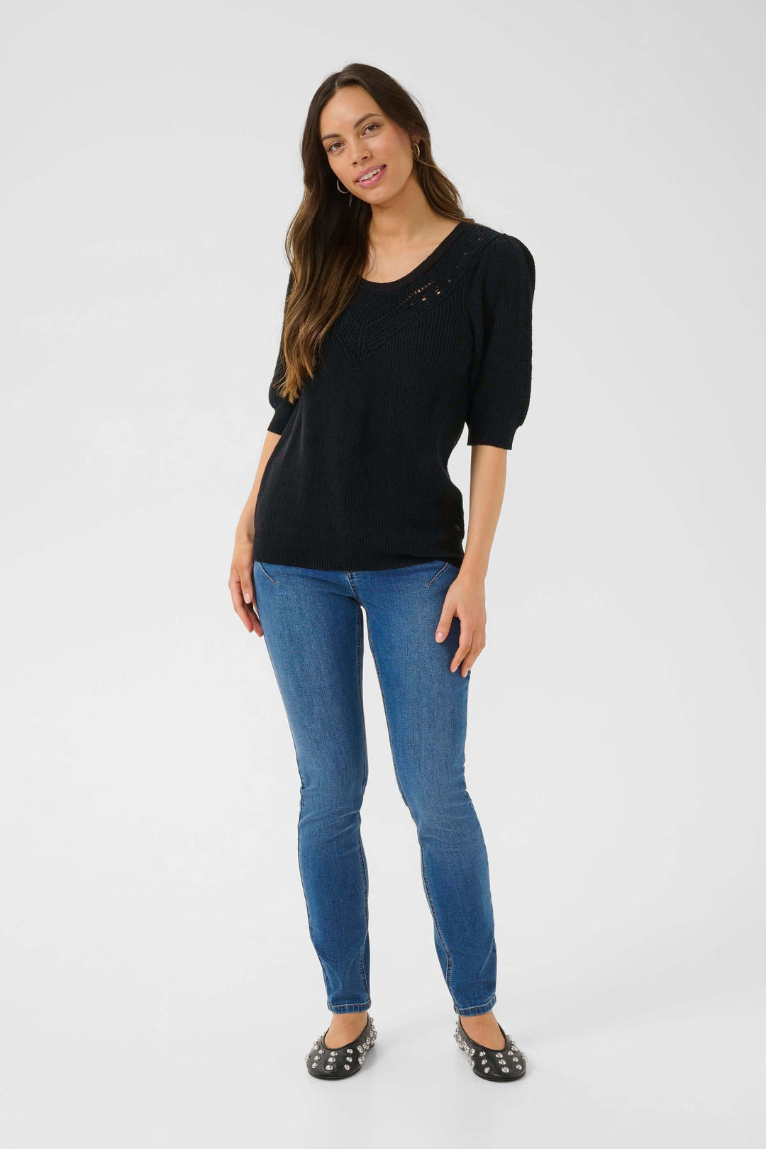 Chandail en tricot Dela noir avec motif ajouré et manches trois-quarts, porté avec un pantalon en denim.