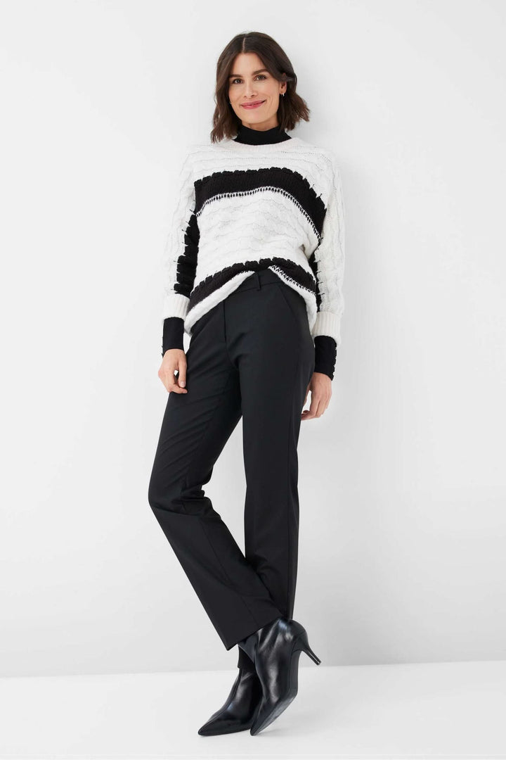 Femme en pull en tricot noir et blanc, pantalon noir et bottines, style décontracté et tendance.
