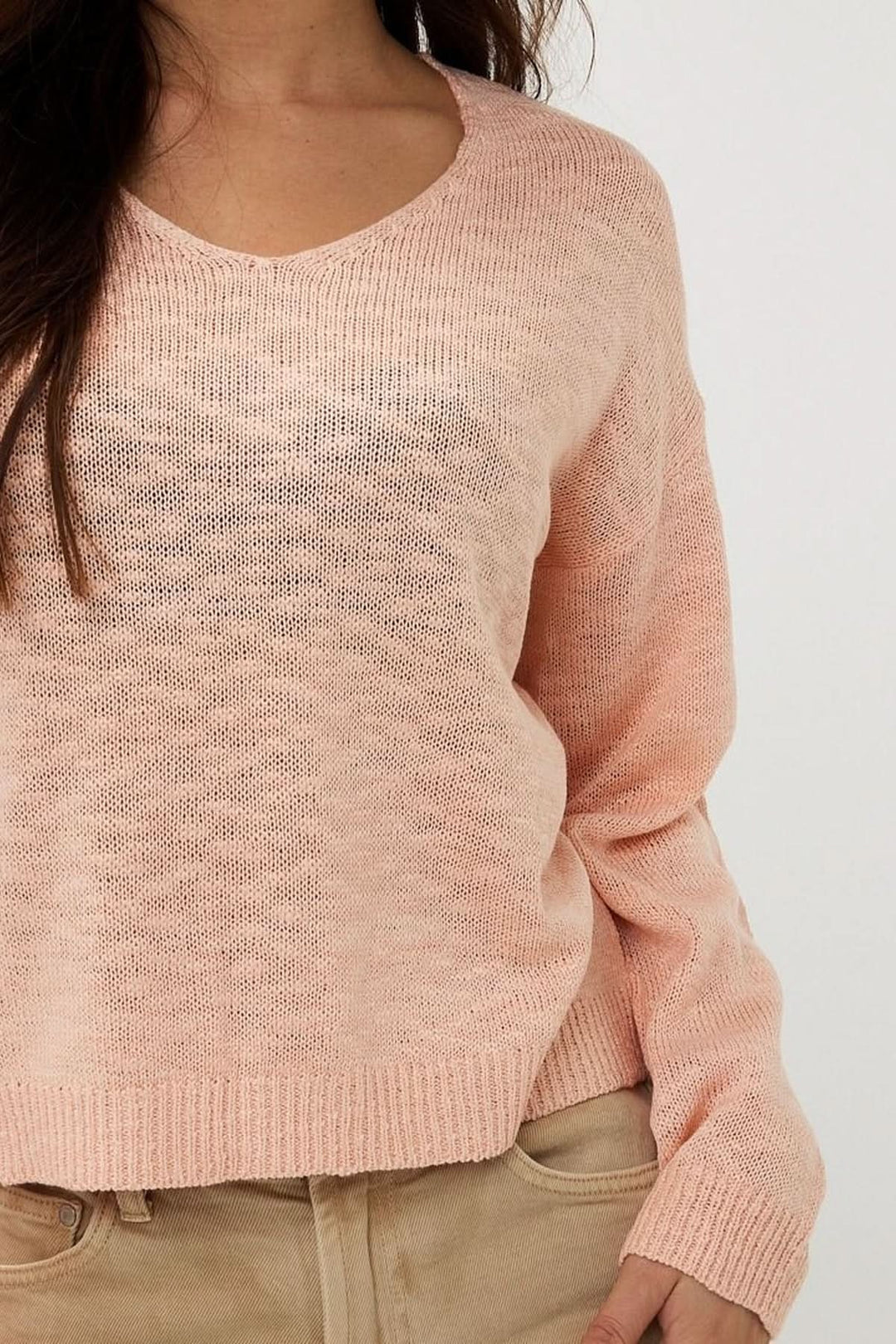 Chandail en tricot ajouré rose clair avec col en V et manches longues, parfait pour un look décontracté.