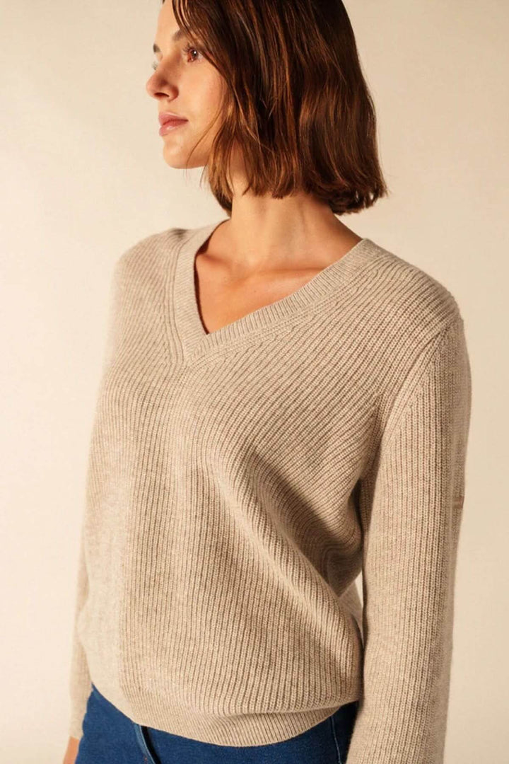 Femme portant un Chandail en tricot à col en V beige, maille côtelée souple, tenue élégante et confortable, vue de profil.