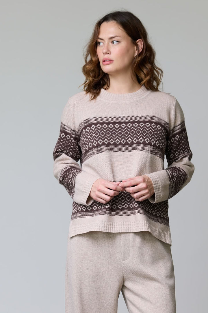 Femme portant un chandail en tricot jacquard avec motif géométrique bicolore et encolure ronde côtelée élégante.