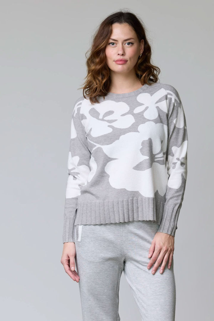 Chandail en tricot à motif floral avec larges fleurs blanches contrastantes, encolure ronde, et finition côtelée pour un look féminin.